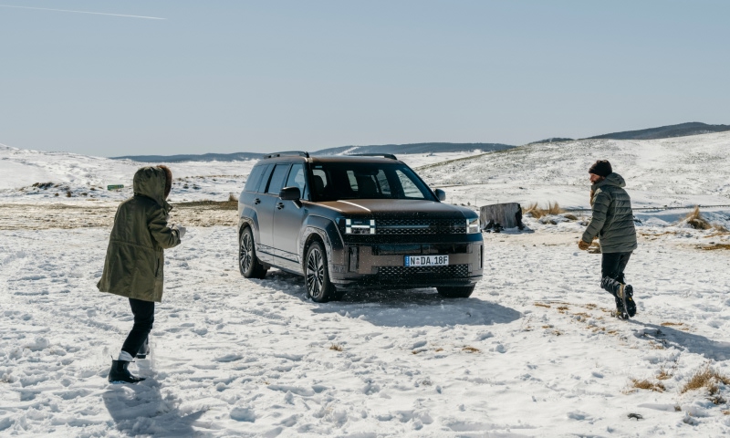 Hyundai SANTA FE Hybrid on the ice with two people throwing snowballs at each other.